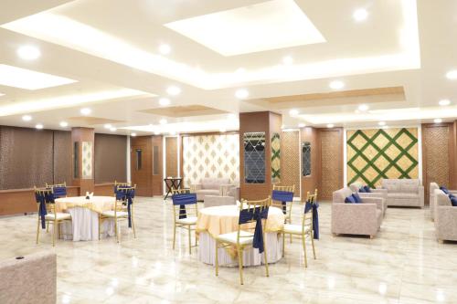 德拉敦Hotel Royal Palm Dehradun的一间在房间内配有桌椅的餐厅