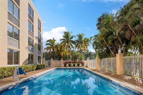 黎明城La Quinta Inn & Suites by Wyndham Sunrise的棕榈树建筑前的游泳池
