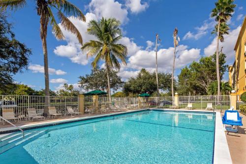 黎明城La Quinta Inn & Suites by Wyndham Sawgrass的一个带椅子的游泳池,棕榈树
