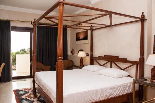 米哈斯Hotel Villarocamar的卧室配有带白色床单的木制天蓬床