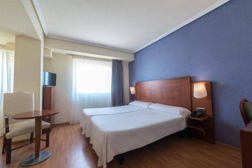 阿尔么丽亚Torreluz Apartamentos的卧室配有白色的床、桌子和窗户。