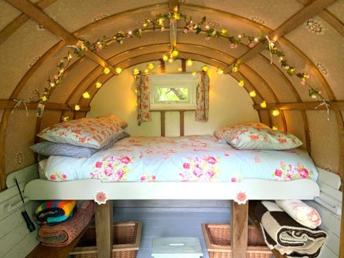 甘尼斯莱克Genuine Gypsy Hut and Glamping Experience - In the Heart of Cornwall的灯火通明的小房子里的一个床位