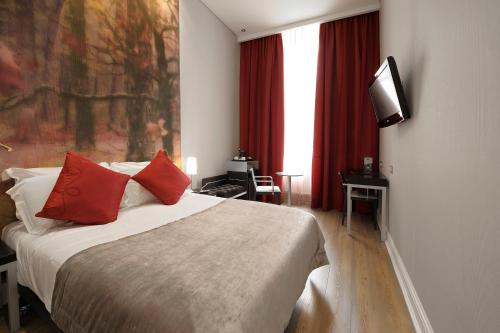 伦敦阿巴伦敦皇后大门酒店的一间卧室配有一张带红色枕头的床和一台电视。
