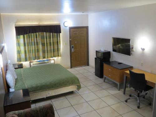 Laguna VistaExecutive Inn Laguna Vista的酒店客房配有一张床、一张书桌和一台电视。