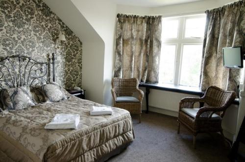卡迪夫格伦代尔酒店的一间卧室配有一张床、两把椅子和一个窗户