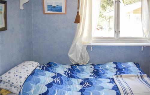 科尔莫登Nice Home In Kolmrden With Kitchenette的一张带蓝色和白色棉被的床和一个窗口