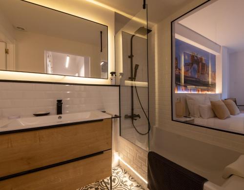毕尔巴鄂Bilbao Henao Park de Bilbao Suites, en pleno centro con garaje directo的一间带水槽和镜子的浴室以及一张床