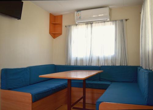 佩尼斯科拉索多尔简易别墅露营酒店的一间设有蓝色沙发、桌子和窗户的客房