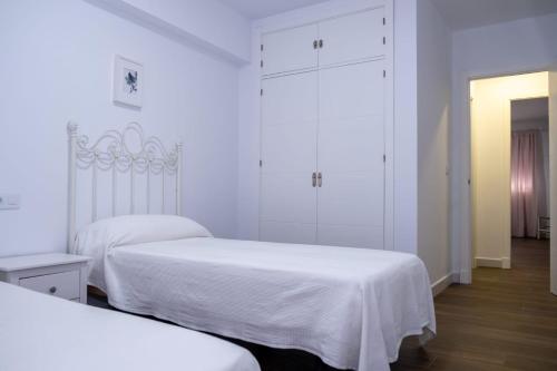 桑卢卡尔-德巴拉梅达Calle Carmen Viejo Apartamento的配有白色墙壁和木地板的客房内的两张床