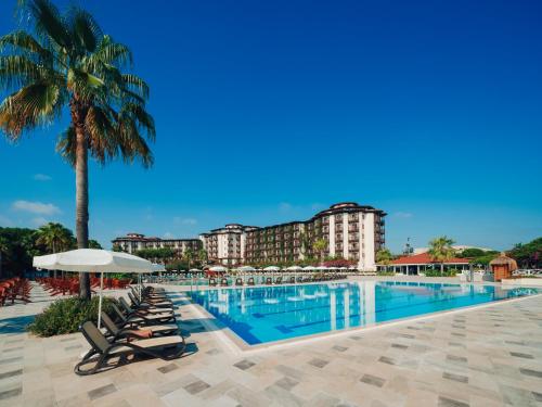 贝莱克Selectum Family Resort Belek的一个带椅子和棕榈树的度假村游泳池