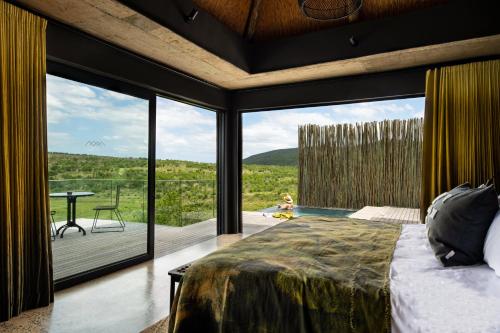 SangoyanamFulaWozi Wilderness Biyela Lodge的一间卧室设有一张床和一个大型玻璃窗