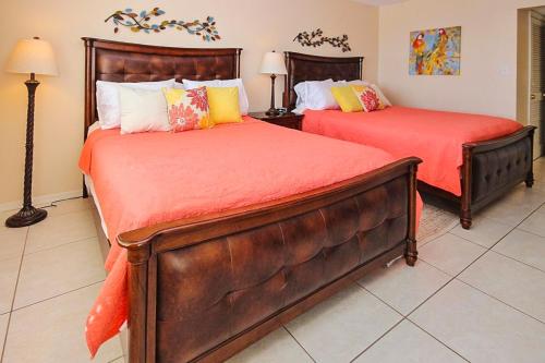 圣徒皮特海滩Sea Breeze 702的一间卧室配有两张带橙色床单的床