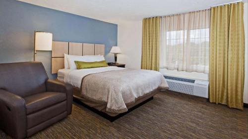 欧弗兰帕克MainStay Suites- Kansas City Overland Park的卧室配有床、椅子和窗户。