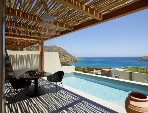 伊罗达Cayo Exclusive Resort & Spa的游泳池旁带桌椅的天井