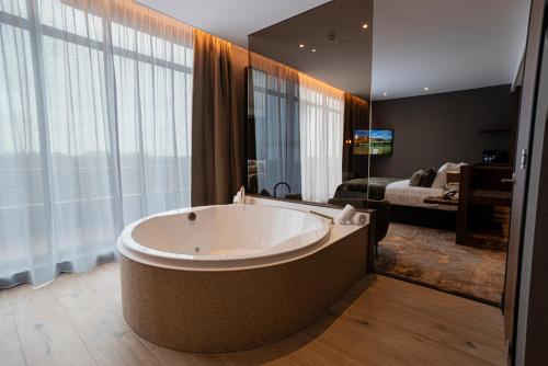 阿尔梅勒阿尔梅勒范德瓦尔克酒店的卧室前设有带大浴缸的大浴室