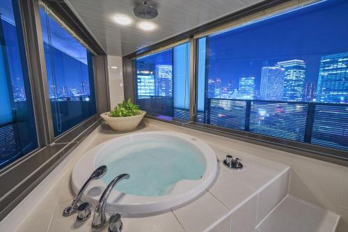 大阪和谐大使酒店的带浴缸的浴室,享有城市景观