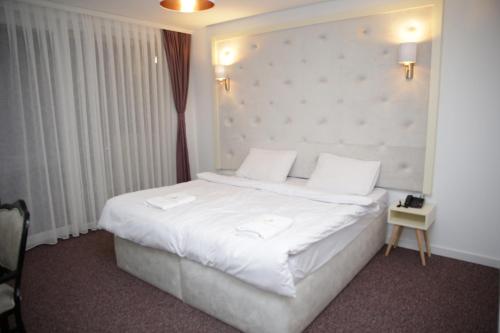 普里什蒂纳Magra Austria Hotel & Restaurant Prishtine的卧室配有一张带白色床单和枕头的大床。