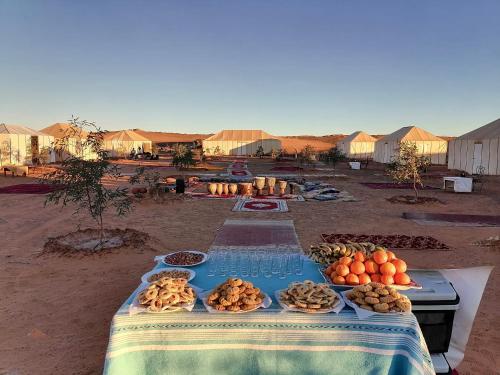 梅尔祖卡Merzouga Camp & Desert Activities的一张桌子,上面有食物在沙漠里
