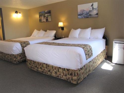 Mountain View熊乡宾馆及套房的配有白色床单的酒店客房内的两张床