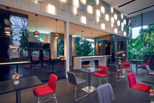 新加坡Quincy Hotel Singapore by Far East Hospitality的一间设有红色桌椅的餐厅和一间酒吧