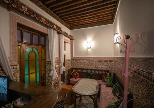 Fès al BaliRiad Dar Barae的客厅设有桌子和彩色玻璃窗