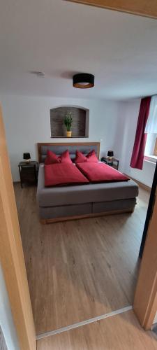 巴特戈特洛伊巴Ferienwohnung Raabsteine的一间卧室配有一张带红色枕头的床