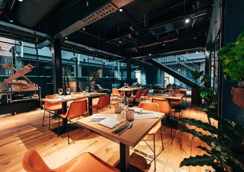 赫尔辛基Hotel Mestari的配有木桌和橙色椅子的餐厅