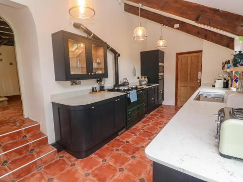 彭赞斯Trevedran Cottage的厨房配有黑色橱柜和红色瓷砖地板。