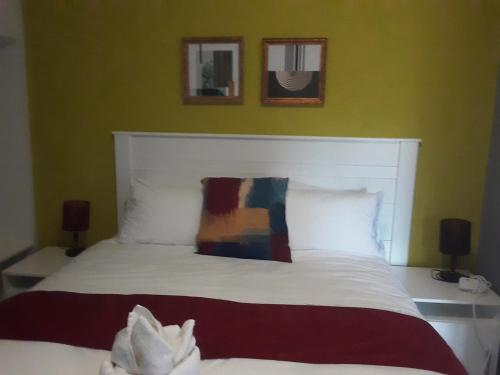 卡萨内Ramatie Guest Palace的卧室配有一张白色床,墙上挂有两张照片