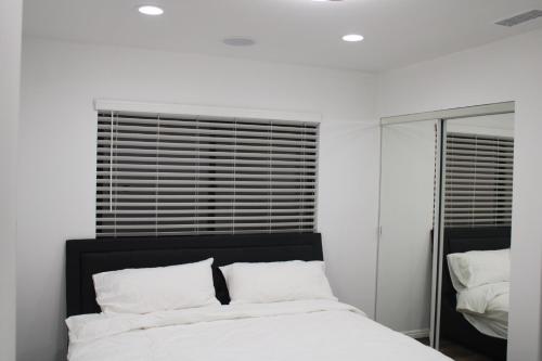 亨廷顿海滩Pearl Beach Villa Huntington Beach的白色卧室配有床和镜子