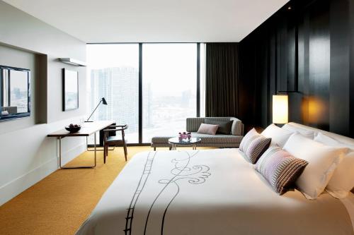 墨尔本皇冠墨尔本大都市酒店的一间卧室配有一张大床、一张桌子和一把椅子