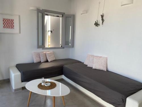 基莫洛斯岛Maganiotis Rooms的客房设有两张床、一张桌子和一扇窗户。