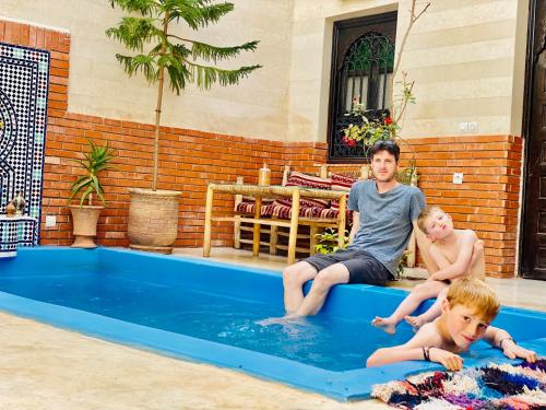 马拉喀什46号摩洛哥传统庭院住宅的坐在游泳池里的男人和两个男孩