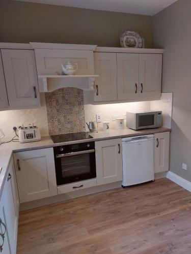 FlorencecourtDrumlaghy House的厨房配有白色橱柜、炉灶和微波炉。