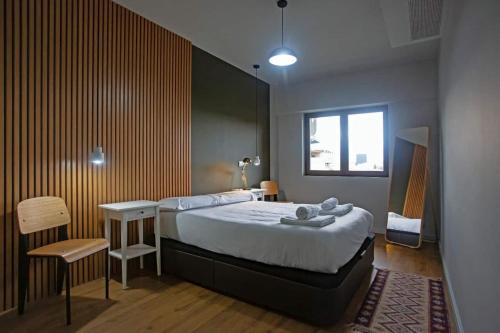 里斯本Luxury apartment near Fonte Luminosa的卧室配有1张床、1张桌子和1把椅子