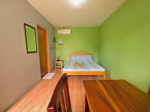 莫阿尔博阿Ananas Guesthouse的卧室设有一张位于绿色墙壁上的床铺