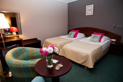 波兹南Hotel Rezydencja Solei的酒店客房,设有两张床和一张鲜花桌。