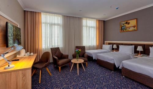 巴库Golden City Hotel Baku的酒店客房带两张床、一张桌子和椅子。