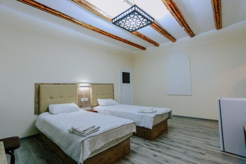 布哈拉BUKHARA HOUSE hotel的配有白色墙壁和天窗的客房内的两张床