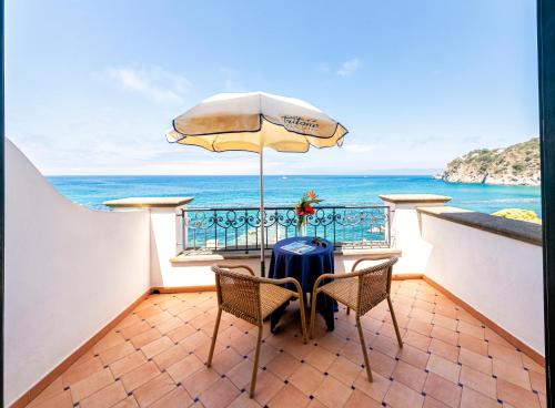伊斯基亚Hotel Terme Tritone Resort & Spa的一张桌子和椅子,配有雨伞和大海