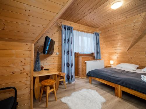 扎科帕内Domki Na Babińcu的小木屋内的卧室,配有一张床和一张书桌
