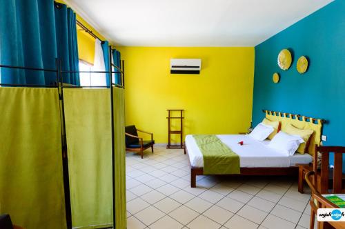 马哈赞加马任加可可酒店及餐厅的一间卧室设有床和黄色及蓝色的墙壁