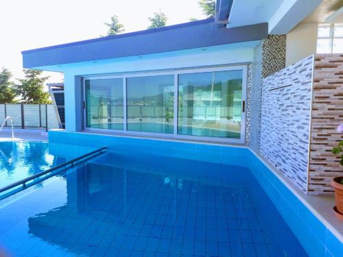 地拉那Luander Hotel的一个带蓝色瓷砖地板和大窗户的游泳池