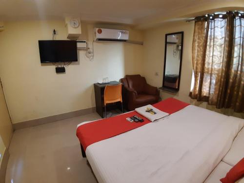 钦奈Hotel Akash inn的一间卧室配有一张床、一把椅子和电视