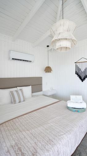 里奥格兰德Picuas Village的白色卧室配有一张带两个吊灯的大床