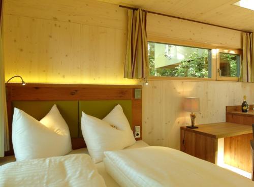 Schrems舒勒姆斯树屋山林小屋的一间卧室配有一张带白色床单的床和一扇窗户。