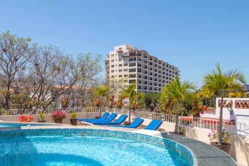 巴亚尔塔港Suites Plaza del Rio - Family Hotel Malecón Centro的一座带蓝色椅子的酒店游泳池以及一座高高的建筑