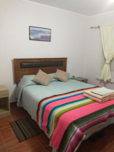 圣佩德罗·德·阿塔卡马Alto Noa San Pedro de Atacama的一间卧室配有一张带彩色毯子的床