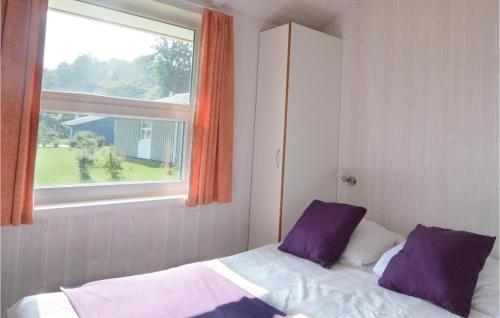 特拉弗明德Strandblick 23 - Dorf 1的窗户客房内的一张带紫色枕头的床