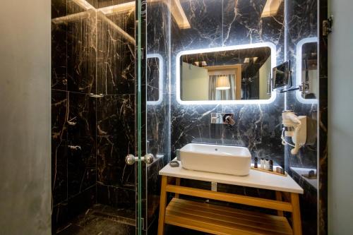 兹拉马GIARDINO High living suites的黑色瓷砖浴室设有水槽和镜子
